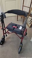 Front view of red Nexus walker showing padded seat, backrest and wheels