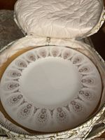 Plate inside round fabric cover showing gold Medina pattern and scalloped edge