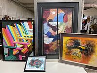 Four framed art prints arranged together showing different abstract and contemporary designs.