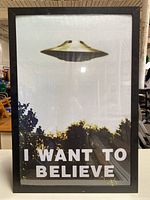 Front view of framed poster showing the UFO above trees and 'I WANT TO BELIEVE' text.