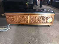 Front view of the Lane cedar chest showing carved wooden panels and tufted black padded top
