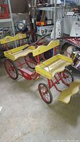 Front and side view showing yellow wooden tandem seats, red frame and wheels