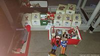 Wide view of collection showing boxed Santa Claus figurines along with loose nutcracker and other Santa Claus figurines in bins