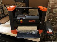 Angled front view of bench-top thickness planer on table