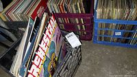 Four plastic milk crates filled with vinyl records, arranged upright to reveal album covers, showing extensive collection with various artists.