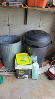 Photo showing three trash bins including metal and plastic bins, ice melt container with yellow lid, and additional cleaning supplies near bins.