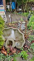 Front view of scalloped basin top with ribbed shell pattern, lying on ground among leaves