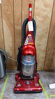 Full front view of a red Bissell PowerForce bagless upright vacuum cleaner showing handle, dust canister, and base with control knob and labels.
