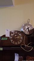 Both clocks displayed together on wooden surface against yellow wall.
