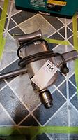 Heavy duty corded drill placed on tiled floor, with power cord wrapped around and side handle attached.