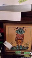 View of the framed indigenous artwork showing the entire figure and wooden frame.