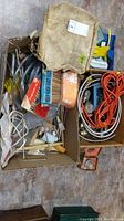 Top view showing packed cardboard boxes containing wood carving tool sets, orange extension cord, canvas bag, painting brushes, and other hardware
