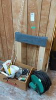 Full view of lot including wooden platform dolly with carpeted top, hardware box with small items, extension cord reel, unopened cement bag, and wood parts.