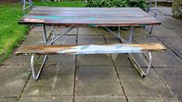 Front view of vintage wood picnic table with metal frame showing wood surface with weathered paint, attached benches, and tubular metal supports.