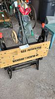 Front view of Black and Decker Workmate 225 with logo visible on wooden surface and golf clubs in background