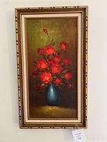 Full view of framed canvas painting showing bouquet of red flowers in blue vase.