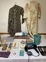 Full lot laid out on a table showing robes, towels, hair dryer, soap dishes, brass towel holders, grooming accessories, and wastebasket.