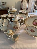 Overview of entire Bavaria porcelain dinnerware lot with plates, cups, teapot, creamer, sugar bowl, platters, and soup tureen arranged on table.
