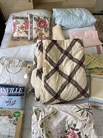 Overall bedding lot items arranged on a bed including pillows, folded sheets, and comforter.