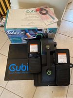 Top view of Cubii JR2 elliptical on mat with box and instructional papers visible.
