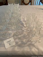 Photo showing 12 wine glasses and 12 liqueur glasses on a table in rows, displaying quantity and style.