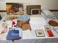 Full lot of kitchen linens, cutting boards, napkin rings, Pimpernel coasters and trivet arranged on table, showing variety of items and condition.