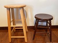 Pair of wooden stools placed on wooden floor, showing difference in height and color.