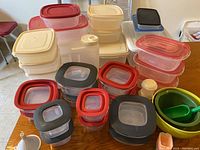 Overview photo showing most plastic storage containers with assorted lids and small bowls with scoop on table
