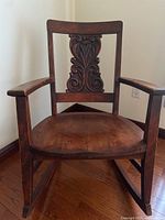 Full view front of wooden rocking chair with carved low profile back and seat