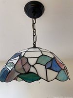 Photo of entire hanging stained glass light fixture showing the dome shape and chain mount.