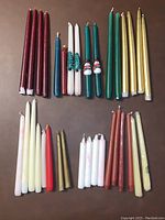 Top-down image showing the full assortment of all decorative candles organized by color and type on a flat surface, illustrating the variety and quantity.