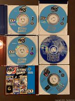 Five computer game discs arranged visible in cases. Four discs labeled Pack's Flying Games numbers 1 to 4, one disc labeled Fighter Pilot. Discs show various game titles.