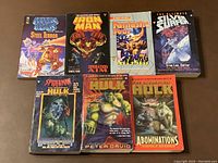 Front covers of the 7 Marvel pocketbooks showing colorful comic artwork and titles under good lighting on a brown surface.