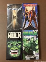 Front view of four VHS cases showing Marvel superhero movies from 2003: X-Men, Daredevil, The Incredible Hulk, and Hulk.