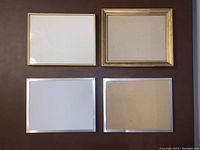 Top-down view of all 4 picture frames laid out on a surface showing two gold-toned and two silver-toned frames.