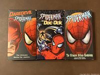 Front covers of three Spider-Man themed VHS tapes arranged side by side on a brown surface showing their artwork and titles.