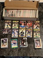 Open box filled with assorted hockey, basketball, and baseball cards fanned out in front