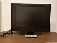 Front view of black Digistar HDTV monitor with screen off. Monitor has a rectangular frame with Digistar logo on the front bottom center and includes a white remote control in front.