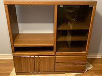 Front view of wooden TV cabinet showing open shelving, glass-front cabinet on the right with shelves, two lower cabinet doors on the left, and three drawers on the right side below glass cabinet