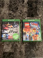 Front of the two Xbox One game cases for The Crew and The Lego Movie Videogame showing cover art and titles.