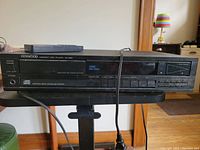 Front view of black Kenwood DP-599 CD player showing model number, disc tray, display, and control buttons.