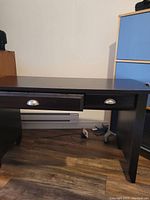 Front view of the dark wood desk showing two drawers with metal cup handles and rectangular top surface.