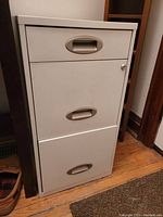 Closed beige metal filing cabinet showing three drawers and key lock.