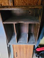 Close view of the storage unit interior showing dividers and a shelf with wear and damage.