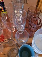 Multiple clear and purple-tinted glasses along with bowls arranged on a flat surface showing various sizes and shapes