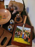 Wooden elephant, pepper grinder with base, painted ceramic cheese board with knife, wooden bowls, salt and pepper shakers on table