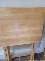 Close-up of a wooden table top showing scratches, marks, and some handwritten numbers.