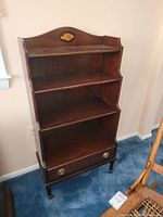 Front view of entire bookcase showing three shelves, lower drawer, legs and casters