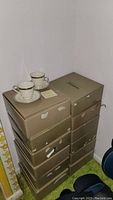 Stack of gold Noritake boxes with two teacups and saucers on top