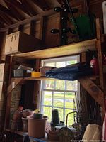 Wide view of shelves with various plastic plant pots in different colors and sizes, some smaller pots stacked, plus hand watering devices and some plant cages or wire frames.